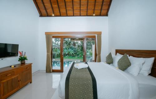 a bedroom with a bed and a television in it at Uma Jala Villa Ubud in Ubud