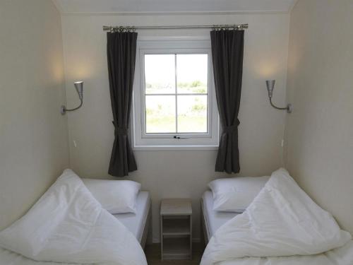 una habitación con dos camas y una ventana en Chalet in Texel with Private Sauna, en Den Hoorn