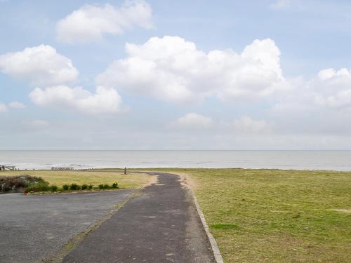 a road leading to a beach with the ocean at Plas Bach in Llanon