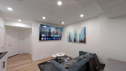 a living room with a couch and a tv on a wall at Cozy 2-Bedroom Basement Suite Just Minutes from the Airport in Calgary