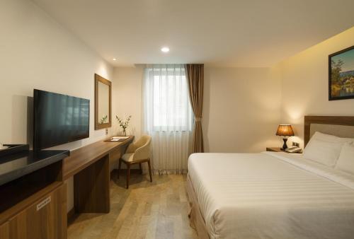 a hotel room with a bed and a flat screen tv at Celine Express - Q Dalat Hotel in Da Lat