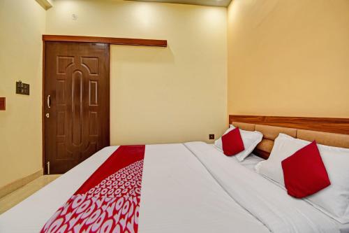 a bedroom with a bed with red and white pillows at Hotel O The Honey Guest House in Haldwāni