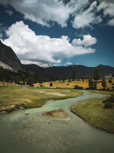 a river in a field with mountains in the background at BOJOL Guesthouse Bilamick in Rondu