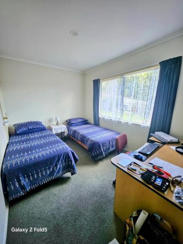 a room with two beds and a desk and a desk at Welcomebay Haven in Tauranga