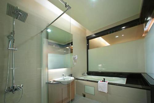 a bathroom with a sink and a shower with a mirror at Shinkansen Grand Hotel in Taichung