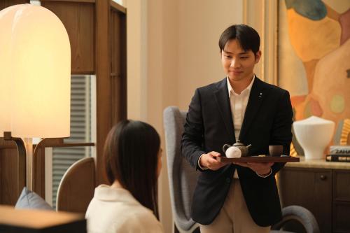a man in a suit holding a tray with a tea pot at Capella Taipei in Taipei