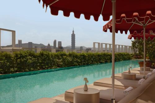 a swimming pool with lounge chairs and an umbrella at Capella Taipei in Taipei