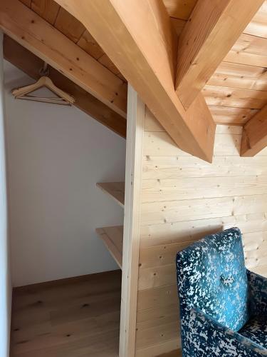 a room with a wooden ceiling and a blue chair at Apartments Antersi Maria in San Vigilio Di Marebbe