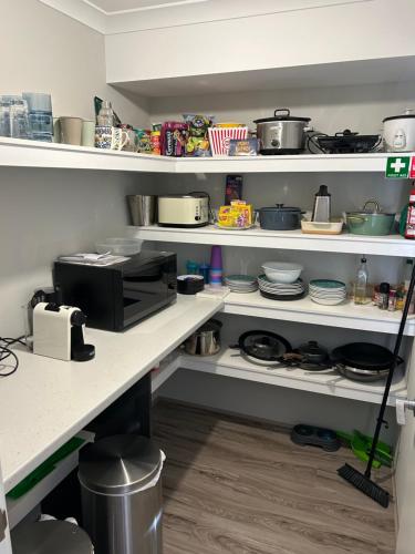 a kitchen with white shelves with pots and pans at Myalup Retreat in Binningup