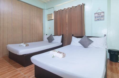 two beds in a room with white sheets at En Gedi Beach Resort by RedDoorz in Iba