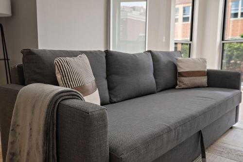 a gray couch with pillows on it in a living room at CozySuites Mill District with pool gym #12 in Minneapolis
