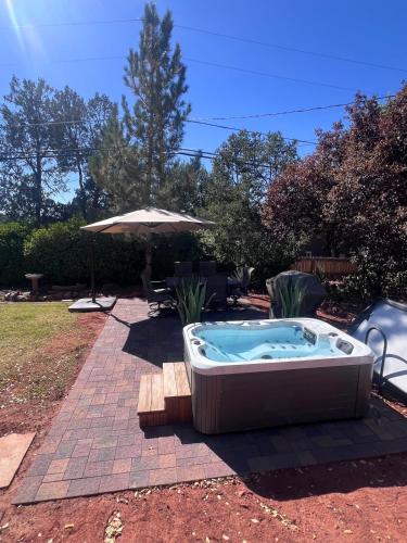 a hot tub in a yard with an umbrella at Mountain Shadows Escape with a Yoga Studio! in Sedona