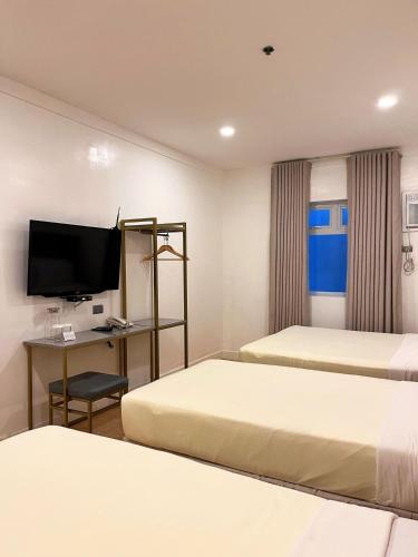 a hotel room with two beds and a desk with a television at ILOILO GRAND HOTEL in Iloilo City