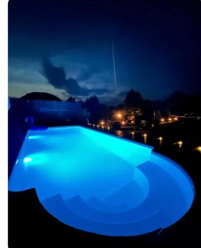 a blue swimming pool lit up at night at AURA - przytulny drewniany domek na wsi in Krzesimów