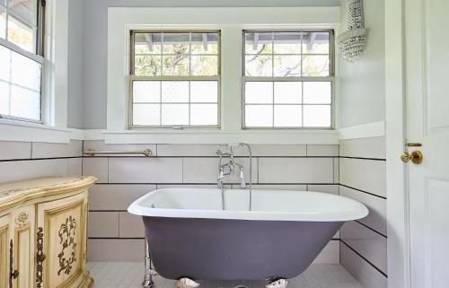 a bath tub in a bathroom with two windows at Luxurious Hollywood Homestay in Los Angeles