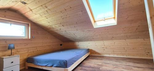 a bed in a wooden room with two windows at AURA - przytulny drewniany domek na wsi in Krzesimów