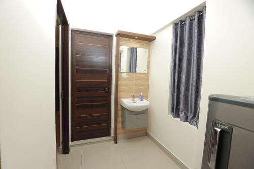 a bathroom with a sink and a wooden door at PLATiNUM AIRPORT LOUNGE in Nedumbassery