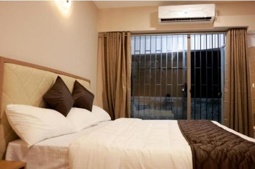 a bedroom with a bed and a window with a balcony at PLATiNUM AIRPORT LOUNGE in Nedumbassery