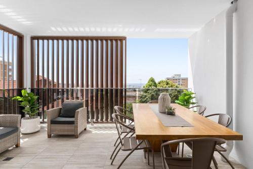 a dining room with a table and chairs and a large window at Azure Apartments Bondi by Urban Rest in Sydney