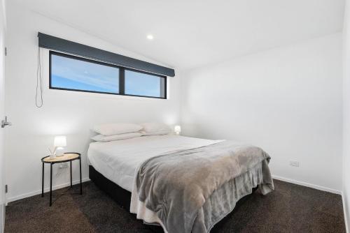 Un dormitorio blanco con una cama y una ventana. en The Sun Trap - Waihi Beach Holiday Home, en Waihi Beach
