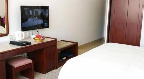 a bedroom with a bed and a desk with a television at Quanzhou Royal Prince Hotel in Quanzhou