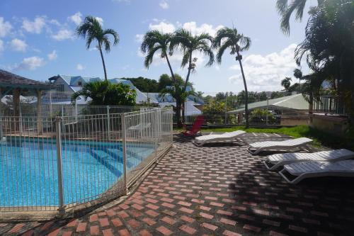 a swimming pool with lounge chairs and palm trees at APPARTEMENT CAMELIA 2 avec PISCINE et à 3 min de la PLAGE Pointe Marin in Sainte-Anne