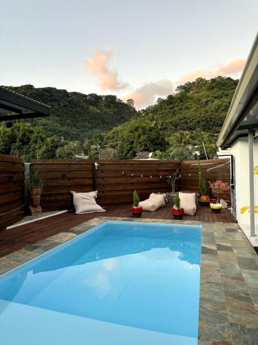 a blue swimming pool on a patio with a mountain at Fare Mananui in Paea