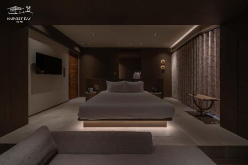 a bedroom with a large white bed and a couch at Harvest Day Hoi An in Hoi An