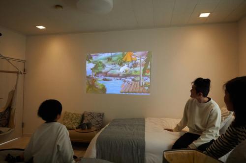 a group of people sitting on a bed in a room at KOEDO MINAMI noyado in Kawagoe