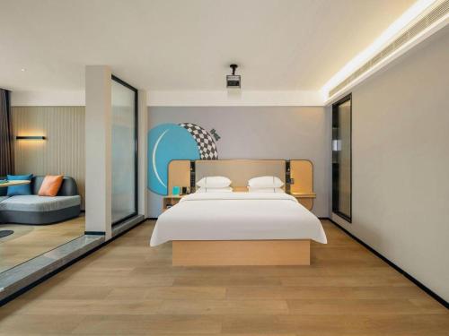 une chambre avec un grand lit blanc et un canapé dans l'établissement City Comfort Inn Hechi Yizhou Erqiao, à Qingyuan