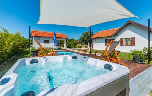 a hot tub in a backyard with an umbrella at Awesome Home In Benkovac With Jacuzzi in Benkovac