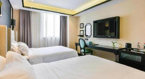 a hotel room with two beds and a desk and a television at Xana Hotelle Wuxi Railway Station Zhongshan Road in Wuxi