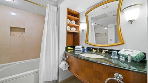 a bathroom with a sink and a mirror and a tub at CozySuites Modern Studio Condo at Showboat #29 in Atlantic City