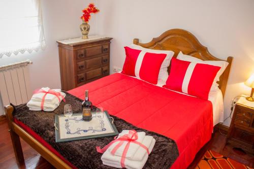 a bedroom with a red bed with a tray with a bottle of wine at Escondidinho do Vez, LDA in Arcos de Valdevez