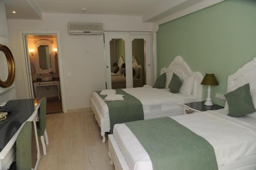 a hotel room with two beds and a mirror at Montebello Deluxe Hotel in Oludeniz