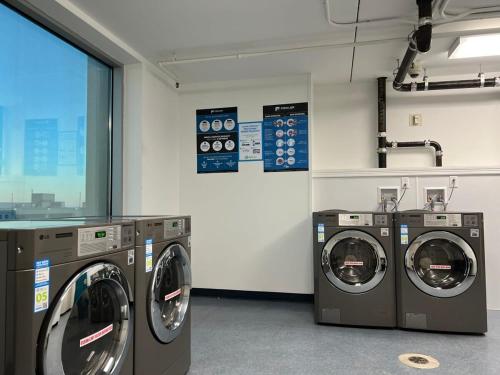 a laundry room with three washing machines and a window at CozySuites Modern Studio Condo at Showboat #30 in Atlantic City
