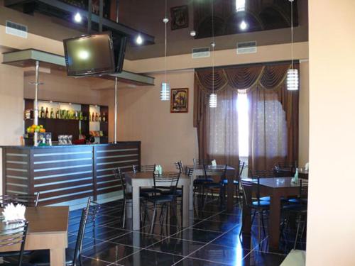 a restaurant with tables and a bar and a television at Hotel Prestige in Astrakhan