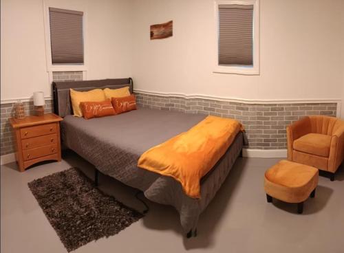 a bedroom with a bed with an orange blanket and a chair at The Reel Freedom Cottage at Leesville Lake in Carrollton