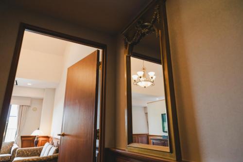 a mirror in a room with a couch and a chandelier at Higashikawa Asahidake Onsen Hotel Bear Monte in Higashikawa