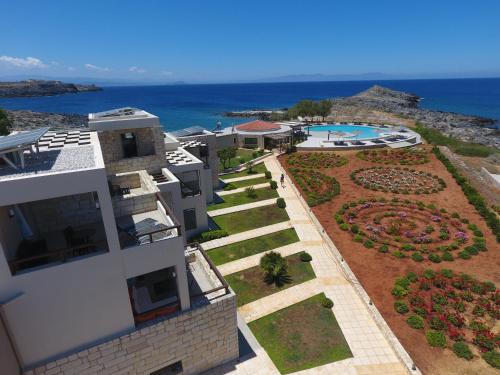 an aerial view of a building with a garden and the ocean at Kavos Hotel & Suites in Stavros