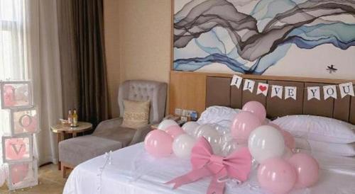 a bedroom with a bed with pink balloons on it at Venus Royal Hotel Nanning East High-Speed Railway Station in Nanning