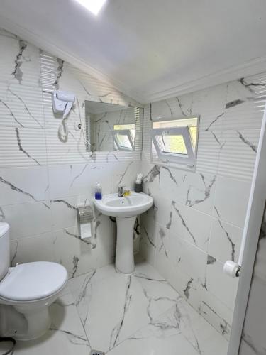 a white bathroom with a toilet and a sink at Buo's guest house in Borjomi