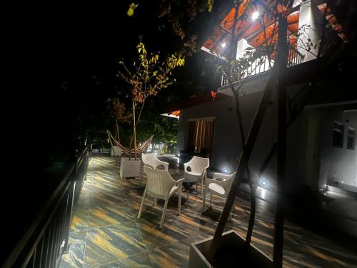 a patio with white chairs and a table at night at Villa Sole in Kandy