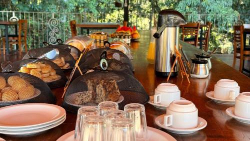 a table with food on it with plates and cups at Pousada de Campo Estância Bahamas in Pirenópolis
