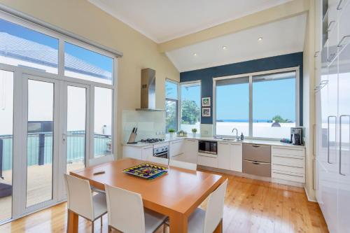 a kitchen with a table and chairs and windows at Scarborough Seaview on Brighton in Perth