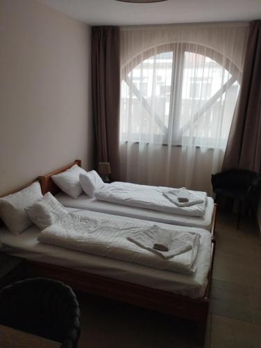 two beds in a room with a window at Régi Posta Hotel és Étterem in Debrecen
