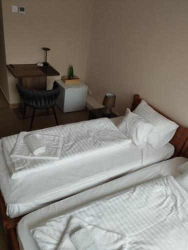 a bedroom with a bed with white sheets and a desk at Régi Posta Hotel és Étterem in Debrecen