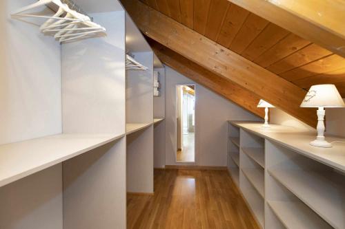 an attic hallway with white shelves and a wooden ceiling at Refugio del Roble by BeValle in Panticosa