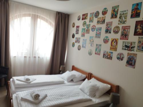 a bedroom with two beds and pictures on the wall at Régi Posta Hotel és Étterem in Debrecen