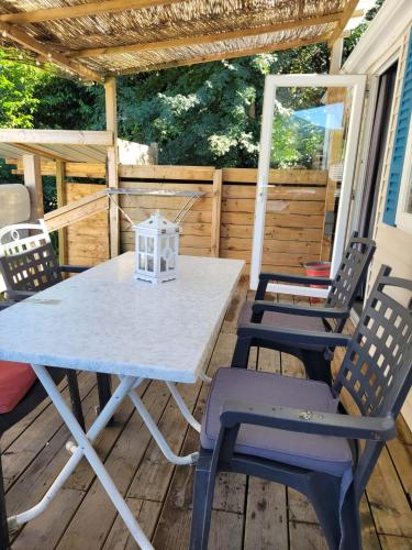 - une table de pique-nique et des chaises sur une terrasse couverte dans l'établissement Camping Le Hameau Des Pécheurs, à Novalaise